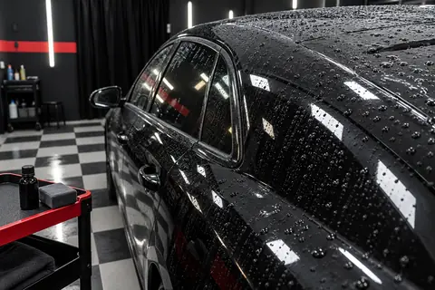 Carro preto com gotas de água após proteção cerâmica na oficina