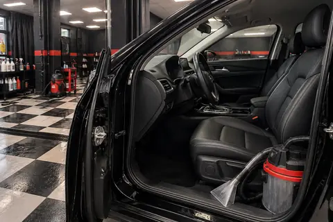 Interior de carro preto sendo preparado para higienização dentro da loja