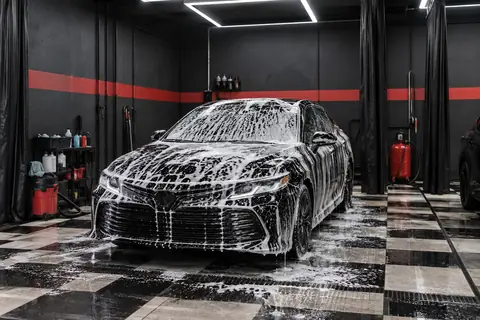 Carro preto coberto de espuma dentro da estética automotiva